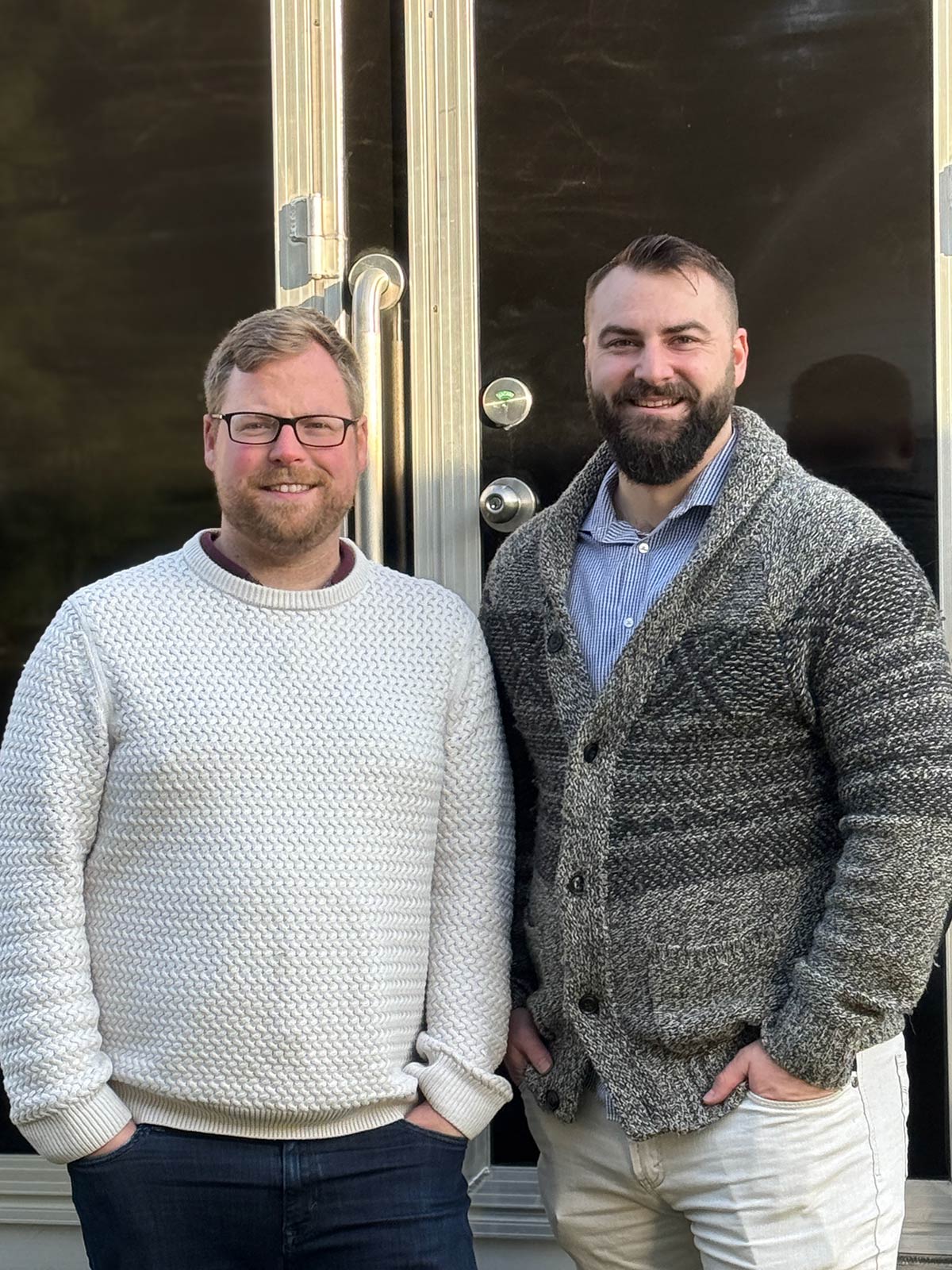 Two men standing by a door.