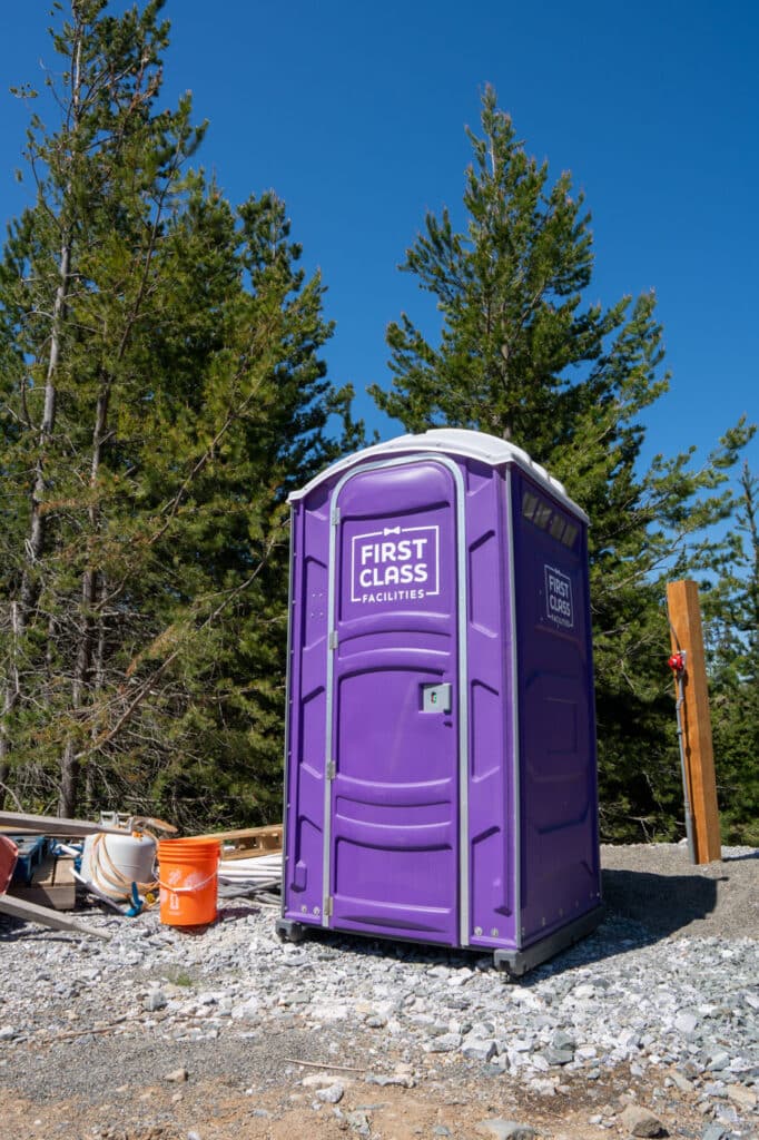 Purple portable toilet in forested area